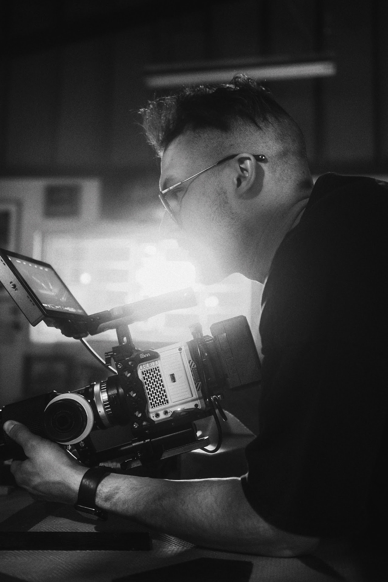 A film reel with a black film strip coiled around its spool sitting on a wooden table. The film is slightly curved as it e...